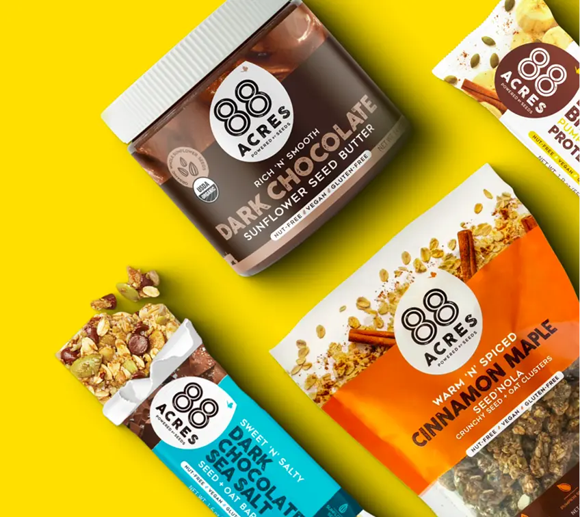 88 Acres Dark Chocolate Sunflower Seed Butter, bars, and granola arranged on a yellow background for healthy product assortment management.