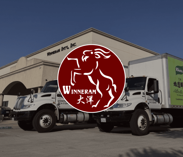 Two Winneram International trucks parked by a beige building with company name, overlaid by a maroon leaping ram Winneram logo.