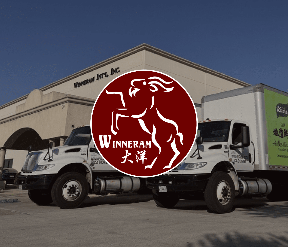 Two Winneram International trucks parked by a beige building with company name, overlaid by a maroon leaping ram Winneram logo.
